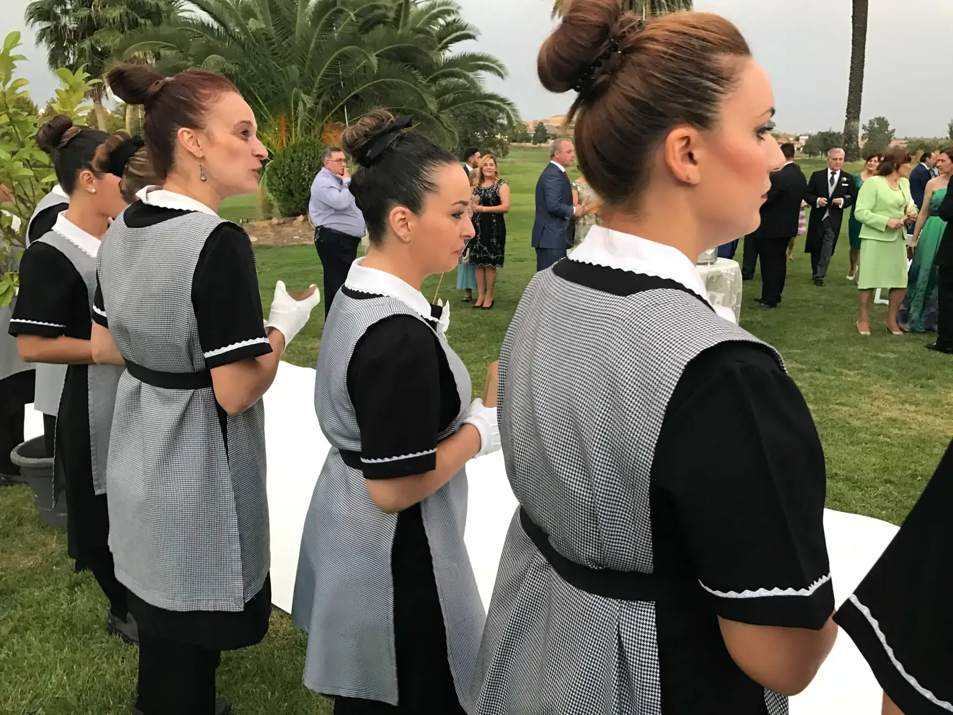 Personal de servicio uniformado atendiendo un evento en los jardines
